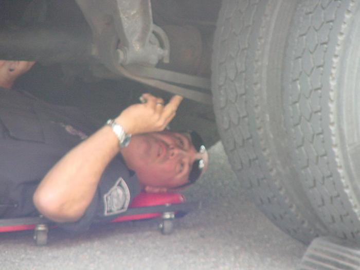 A police officer inspecting the bottom of a truck.