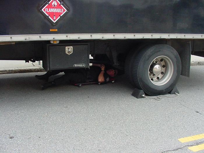 A police officer inspecting the bottom of a truck.